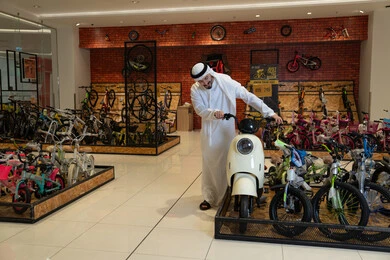 Emirati Man Inspecting Electric Scooter in Bicycle Shop