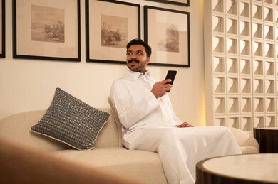 Saudi Man Using Smartphone on Sofa in Modern Living Room