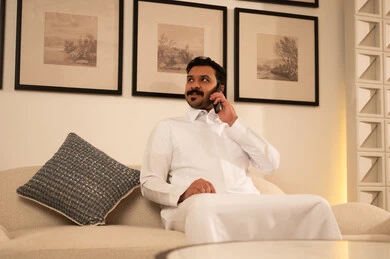 رجل عربي بالثوب التقليدي يتحدث عبر الهاتف الذكي