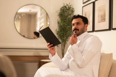 Middle Eastern Man in Thobe Thinking While Reading a Book