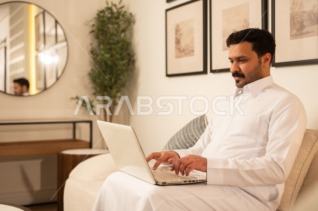 رجل سعودي يستخدم اللابتوب في غرفة معيشة حديثة