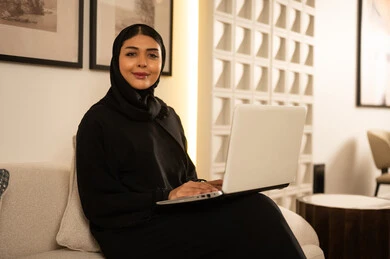 امرأة سعودية مع كمبيوتر محمول في غرفة معيشة حديثة