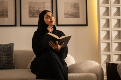 Saudi Woman Reading Book in Warm Indoor Setting