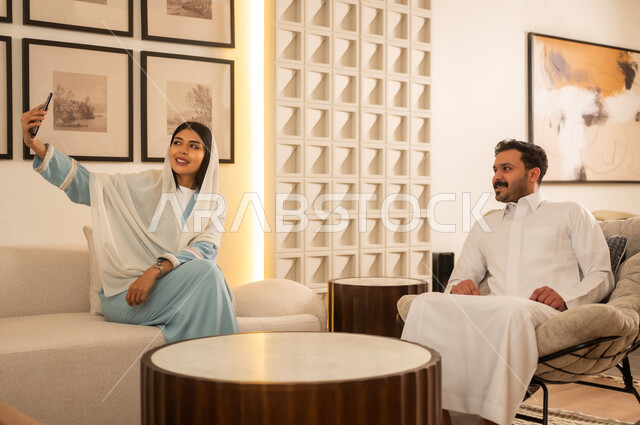 زوجين سعوديين يلتقطان صورة سيلفي في غرفة معيشة حديثة