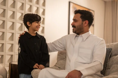 Saudi Father and Son Smiling in Modern Living Room Saudi Father and Son Smiling in Modern Living Room