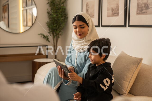 امرأة عربية وطفل يستخدمان الجهاز اللوحي في المنزل