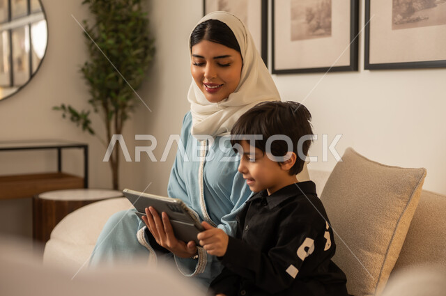 أم سعودية وابنها يستخدمان الجهاز اللوحي في المنزل