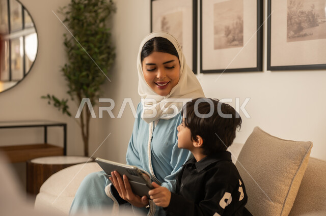 أم سعودية وابنها يستخدمان الجهاز اللوحي في المنزل