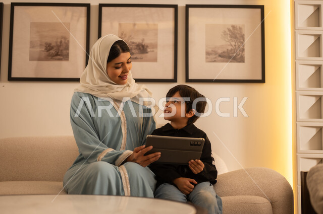 امرأة عربية وطفل يستخدمان الجهاز اللوحي في المنزل