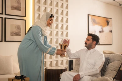 امرأة سعودية تقدم مبخرة لرجل في منزل حديث