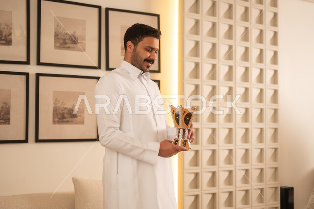 رجل سعودي يحمل مبخرة تقليدية في منزل حديث