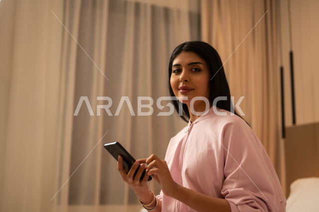 Arab Woman with Smartphone in Bedroom Interior