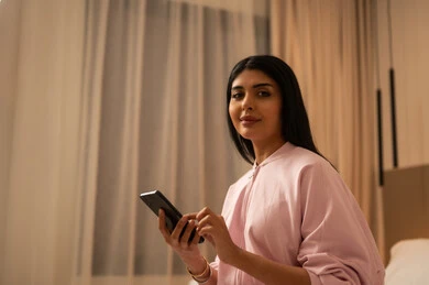 امرأة عربية مع هاتف ذكي في غرفة النوم