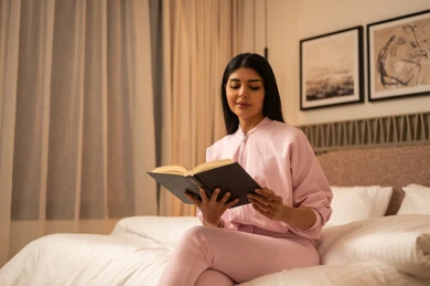 امرأة عربية تقرأ كتاب في غرفة نوم حديثة بالليل