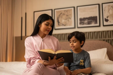 أم عربية تقرأ كتاباً لابنها في غرفة النوم