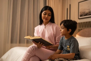 أم عربية تقرأ كتاباً لابنها الصغير في المنزل