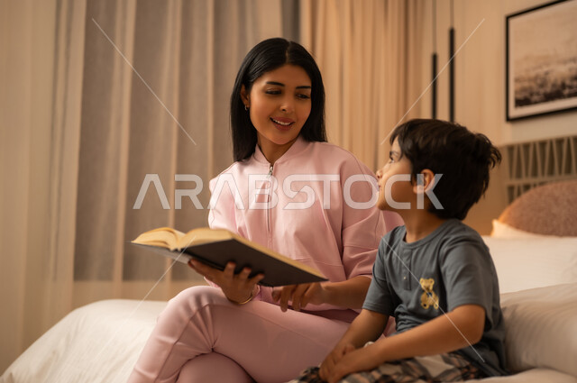 Arab Mother Reading Book to Son in Bedroom