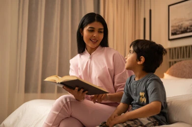 Arab Mother Reading Book to Son in Bedroom