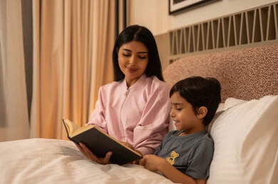 Arab Mother Reading Storybook to Child at Bedtime
