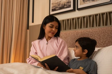 Mother Reading Book to Son in Bedroom