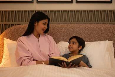 Arab Mother Reading Bedtime Story to Son at Night