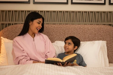 أم عربية تقرأ كتاباً لابنها في السرير ليلاً