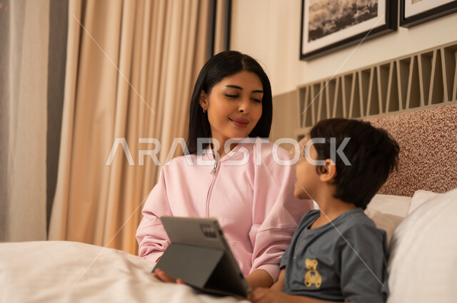 Arab Mother and Son Using Digital Tablet in Bed