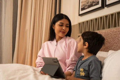 Arab Mother and Son Using Digital Tablet in Bed