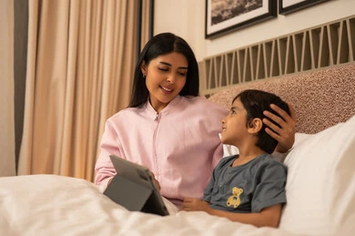 أم عربية وابنها مع جهاز لوحي في غرفة النوم
