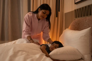 Arab Mother Looking at Her Sleeping Son in Bedroom