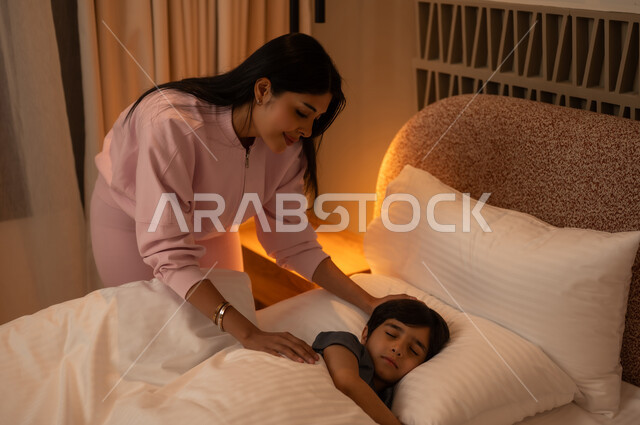 أم تراقب ابنها النائم في السرير بإضاءة دافئة