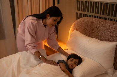 Mother Watching Son Sleep in Bed with Warm Light