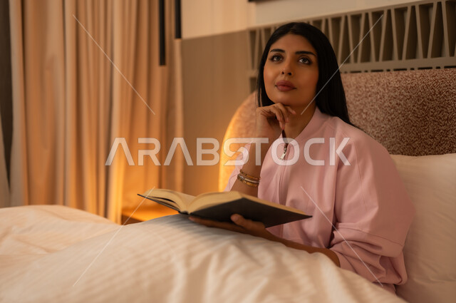 Arab Woman Reading Book in Bedroom Under Warm Light