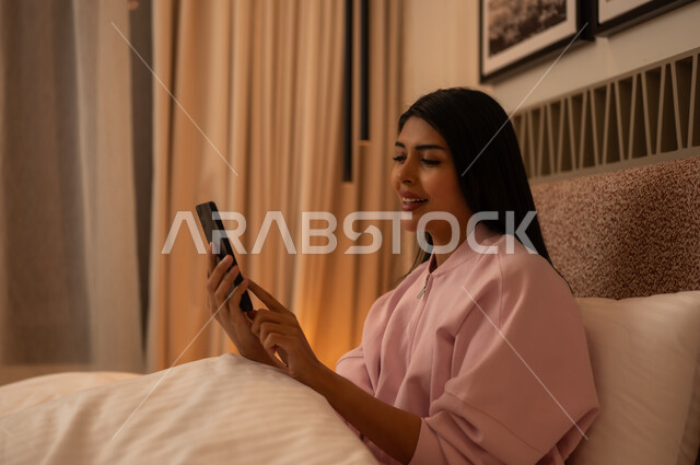 Young Arab Woman Using Smartphone in Bed at Night
