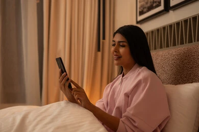 Young Arab Woman Using Smartphone in Bed at Night