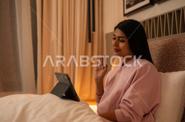امرأة في غرفة النوم تستخدم الجهاز اللوحي للمكالمات المرئية