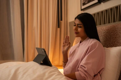 امرأة في غرفة النوم تستخدم الجهاز اللوحي للمكالمات المرئية