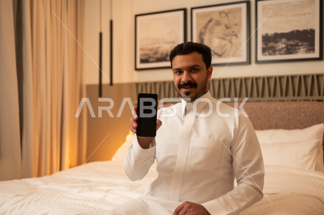Saudi Man Showing Smartphone Screen in Bedroom