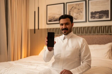 Saudi Man Showing Smartphone Screen in Bedroom