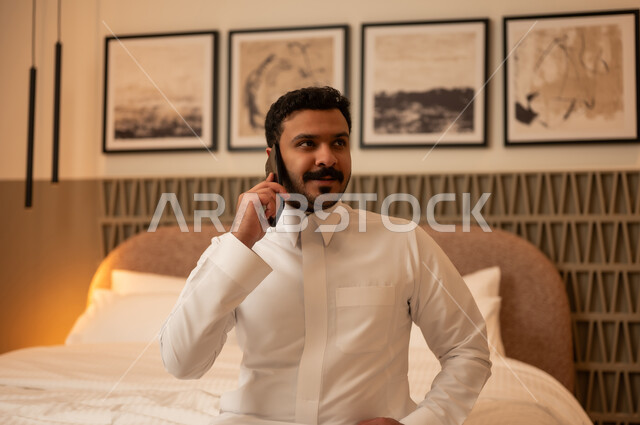 Arab Man in White Thobe Talking on Smartphone in Hotel
