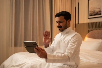 رجل سعودي يستخدم الجهاز اللوحي لمكالمة فيديو في غرفة النوم