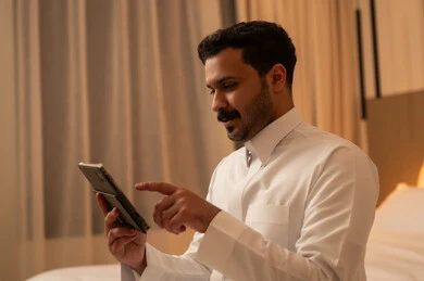 Saudi Man Using Tablet in Bedroom with Warm Lighting