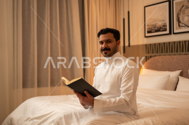 رجل عربي يقرأ كتاباً في غرفة نوم حديثة