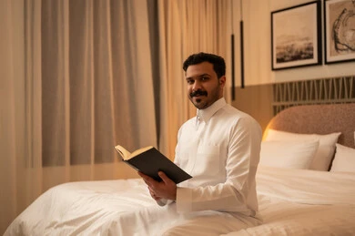 رجل عربي يقرأ كتاباً في غرفة نوم حديثة