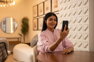 امرأة سعودية تستخدم الهاتف الذكي في غرفة حديثة