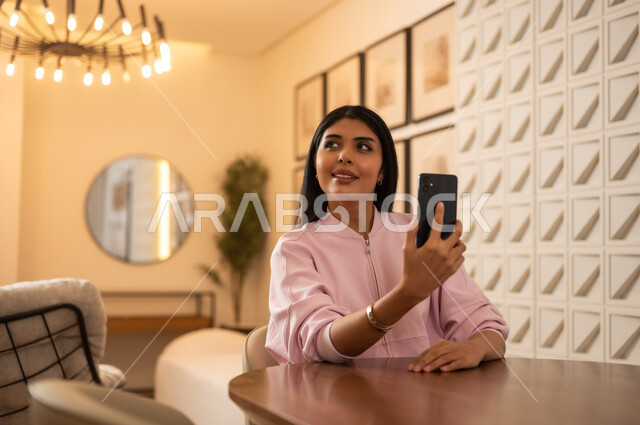 امرأة سعودية مع هاتف ذكي في مقهى حديث