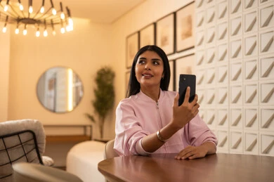 Saudi Woman with Smartphone in Modern Cafe Interior