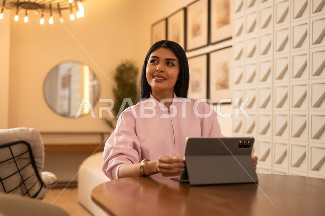 امرأة عربية مع جهاز لوحي رقمي في ديكور حديث