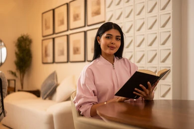 Arab Woman Reading Book in Modern Lounge with Warm Lighting