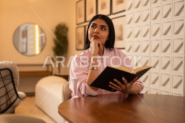 امرأة سعودية شابة تقرأ كتابا في بيئة داخلية حديثة